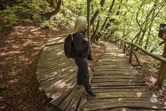 Older Caucasian woman reading sign on wooden pathway in forest