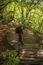 Older Caucasian woman walking on wooden pathway in forest