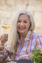 Smiling older Caucasian woman holding white wine