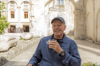 Smiling older Caucasian man drinking coffee in garden