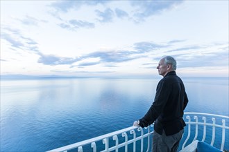 Caucasian man admiring scenic view on waterfront balcony