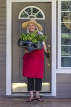 Caucasian woman holding potted plants in doorway