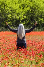 Caucasian woman with arms raised in field of flowers