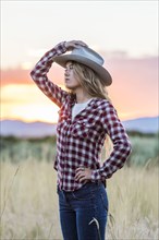 Caucasian teenage girl wearing cowboy hat at sunset