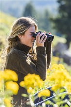 Caucasian girl in field using binoculars