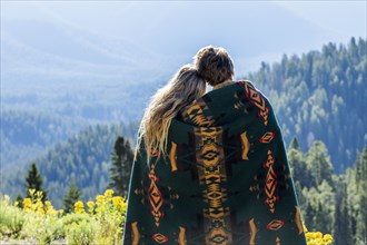 Caucasian couple wrapped in blanket admiring scenic view of landscape