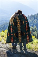 Caucasian couple wrapped in blanket admiring scenic view of landscape