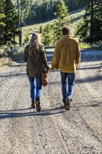 Caucasian couple walking on dirt road holding hands