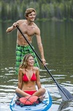Caucasian couple riding paddleboard