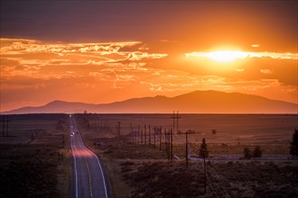 Cars driving on remote road at sunset