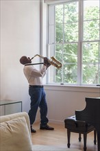 Man playing saxophone near window