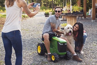 Woman photographing couple and dog with cell phone