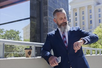 Caucasian businessman checking the time on wristwatch outdoors