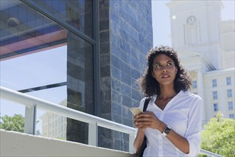 Mixed Race businesswoman texting on cell phone outdoors