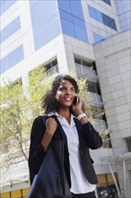 Mixed Race businesswoman talking on cell phone outdoors