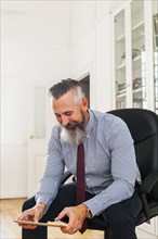Caucasian businessman sitting on chair using digital tablet