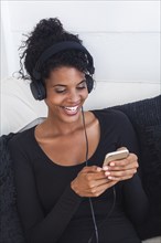 Mixed Race woman listening to cell phone with headphones