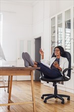 Mixed Race woman with feet up listening to cell phone with headphones