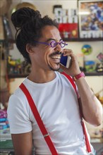 Laughing mixed race man wearing suspenders talking on cell phone