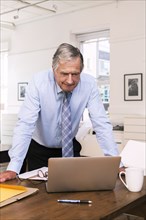 Caucasian businessman leaning on table using laptop