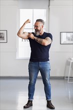 Smiling muscular Caucasian hipster man flexing biceps