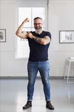 Smiling muscular Caucasian hipster man flexing biceps