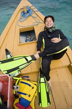 Asian man in scuba gear on boat deck