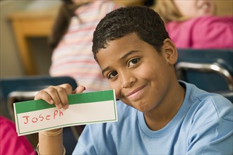 Mixed race school boy holding name card