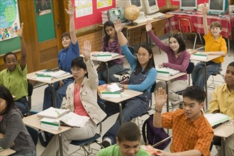 Students raising hands in classroom