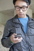 Mixed race teenage boy text messaging with cell phone