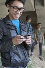 Smiling mixed race teenage boy text messaging with cell phone