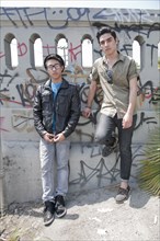 Serious teenage boys leaning against graffiti covered railing