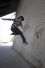 Mixed race teenage boy jumping off wall