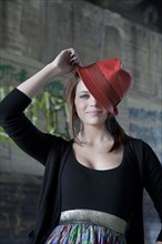Smiling Caucasian teenage girl tipping hat on head