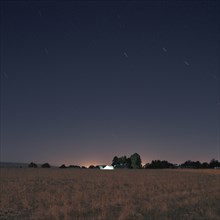 Stars and sunset over field