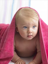 Mixed race baby girl laying under towel