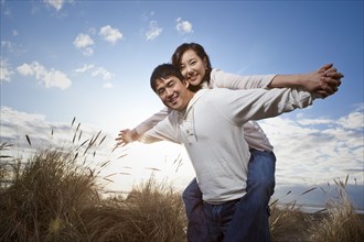Korean man giving girlfriend piggyback ride