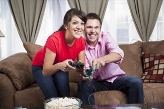 Couple sitting on sofa and playing video game