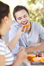 Woman feeding orange to man