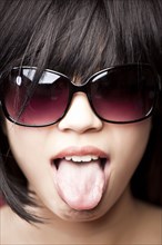 Chinese woman wearing sunglasses and tongue out
