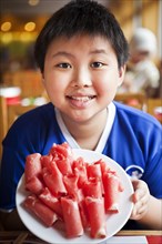 Chinese boy holding plate of rolled meat