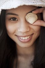 Smiling Chinese woman with shell in front of her eye