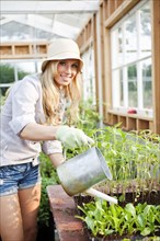 Caucasian woman watering plants in greenhouse
