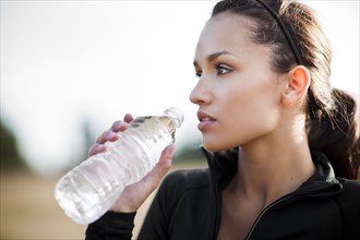 Serious woman in sportswear drinking water