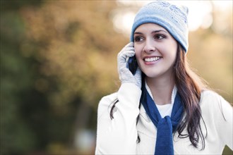 Mixed race woman in cap talking on cell phone