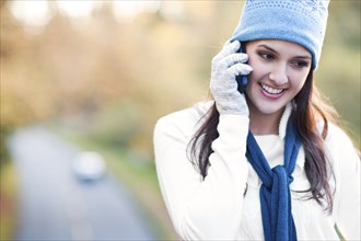 Mixed race woman in cap talking on cell phone