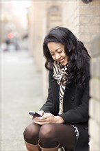 Mixed race woman text messaging on cell phone