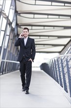 Mixed race businessman walking and talking on cell phone