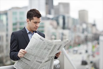 Mixed race businessman reading newspaper