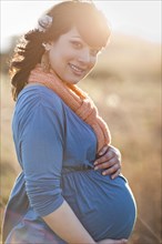 Pregnant mixed race woman holding stomach